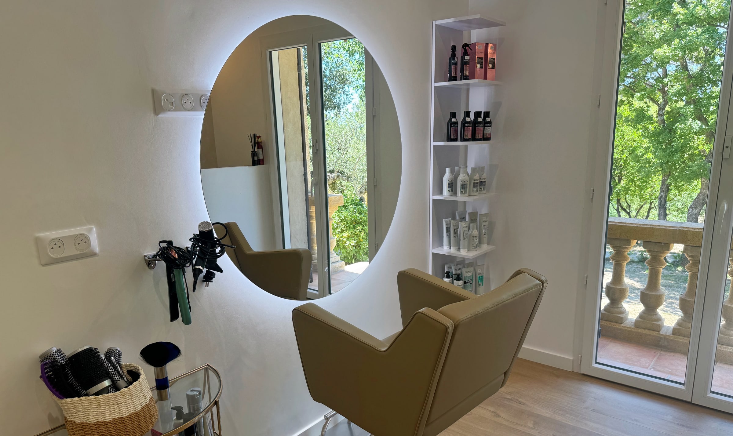 Le miroir rond rétroéclairé et le fauteuil couleur sable du salon